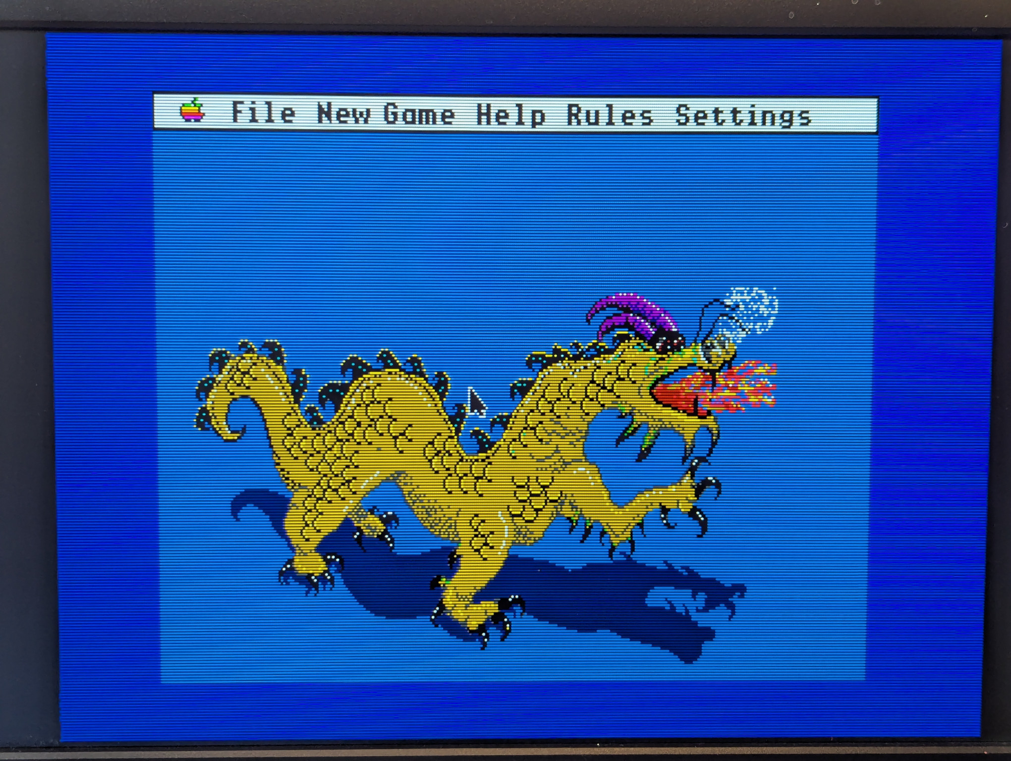 A photograph of the victory screen from the game 'Shanghai' for the Apple IIgs.  A yellow-green dragon with purple horns is breathing fire and snorting smoke.
