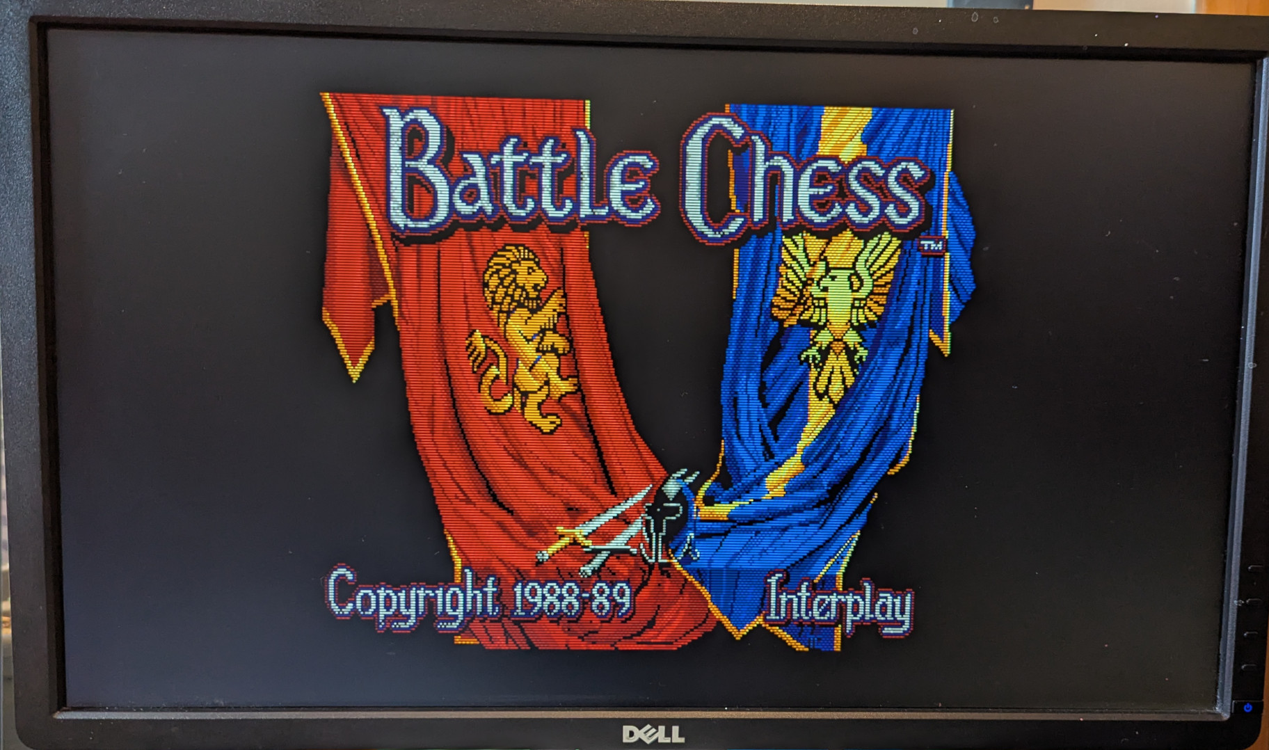 A photograph of the title screen from the game 'Battle Chess' for the Apple IIgs.  A red banner emblazoned with a lion is on the left, facing off against a blue banner with an eagle on the right.
