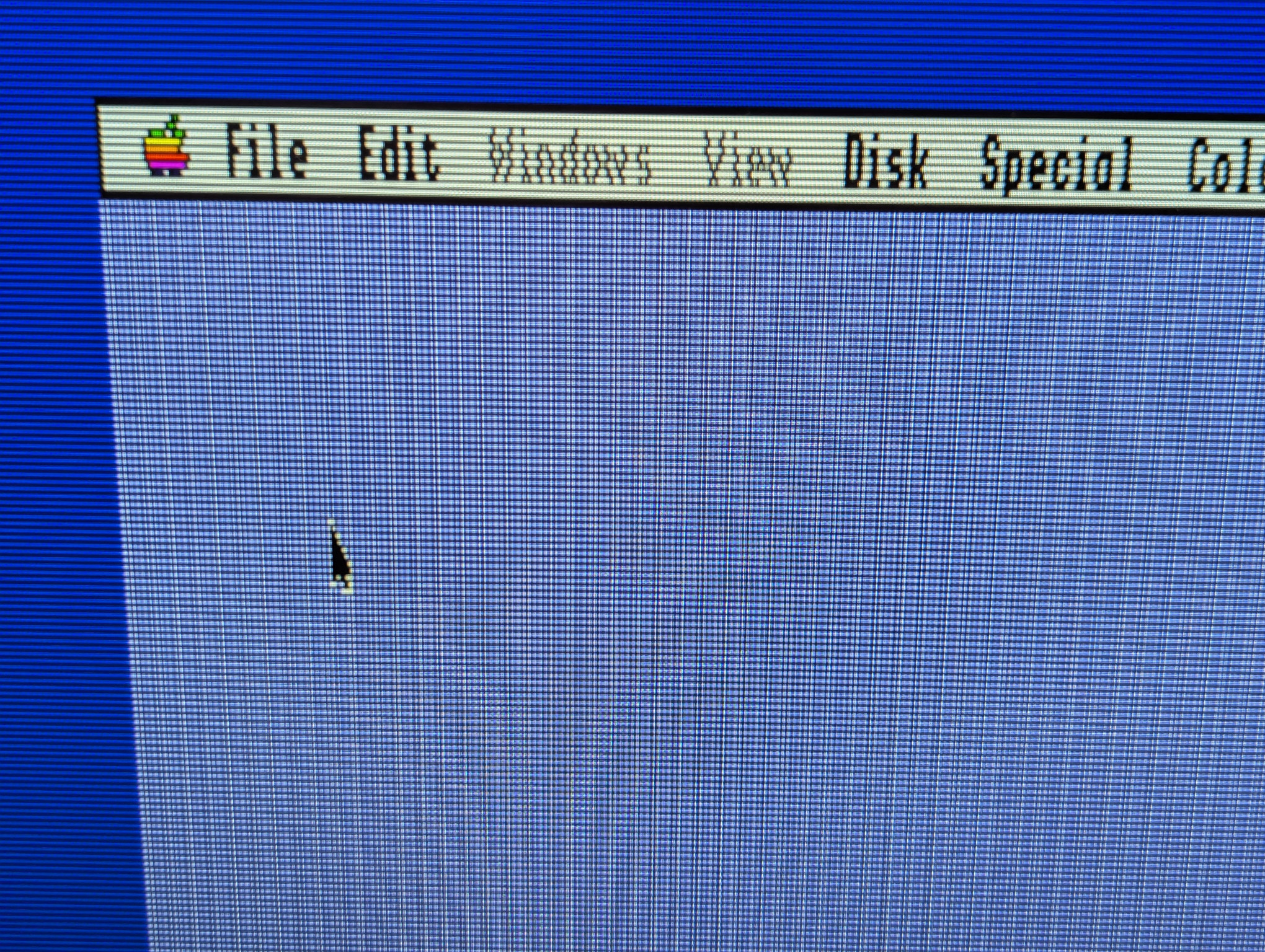 A close-up photograph of a flat panel monitor displaying the GS/OS desktop environment running on an Apple IIgs computer.  The photo is showing the top left corner of the desktop, with the video output running through a GBS-C upscaler.  A 'scanline' shader effect is applied to better approximate the way the picture would have looked on a period-accurate CRT monitor.
